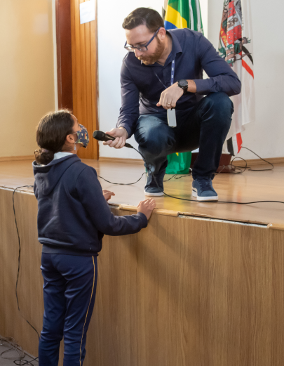 Gerente comercial estendendo o microfone para aluna fazer pergunta a ele